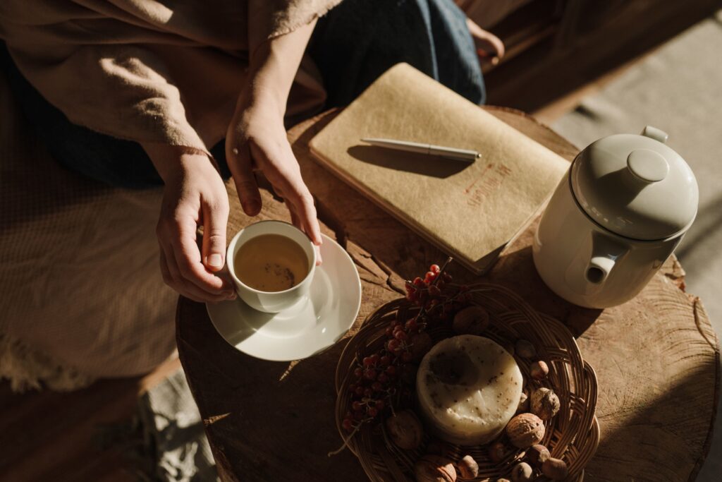 Morning wellness ritual with tea, journal, and natural sunlight representing healthy daily rhythms and mindful living.
